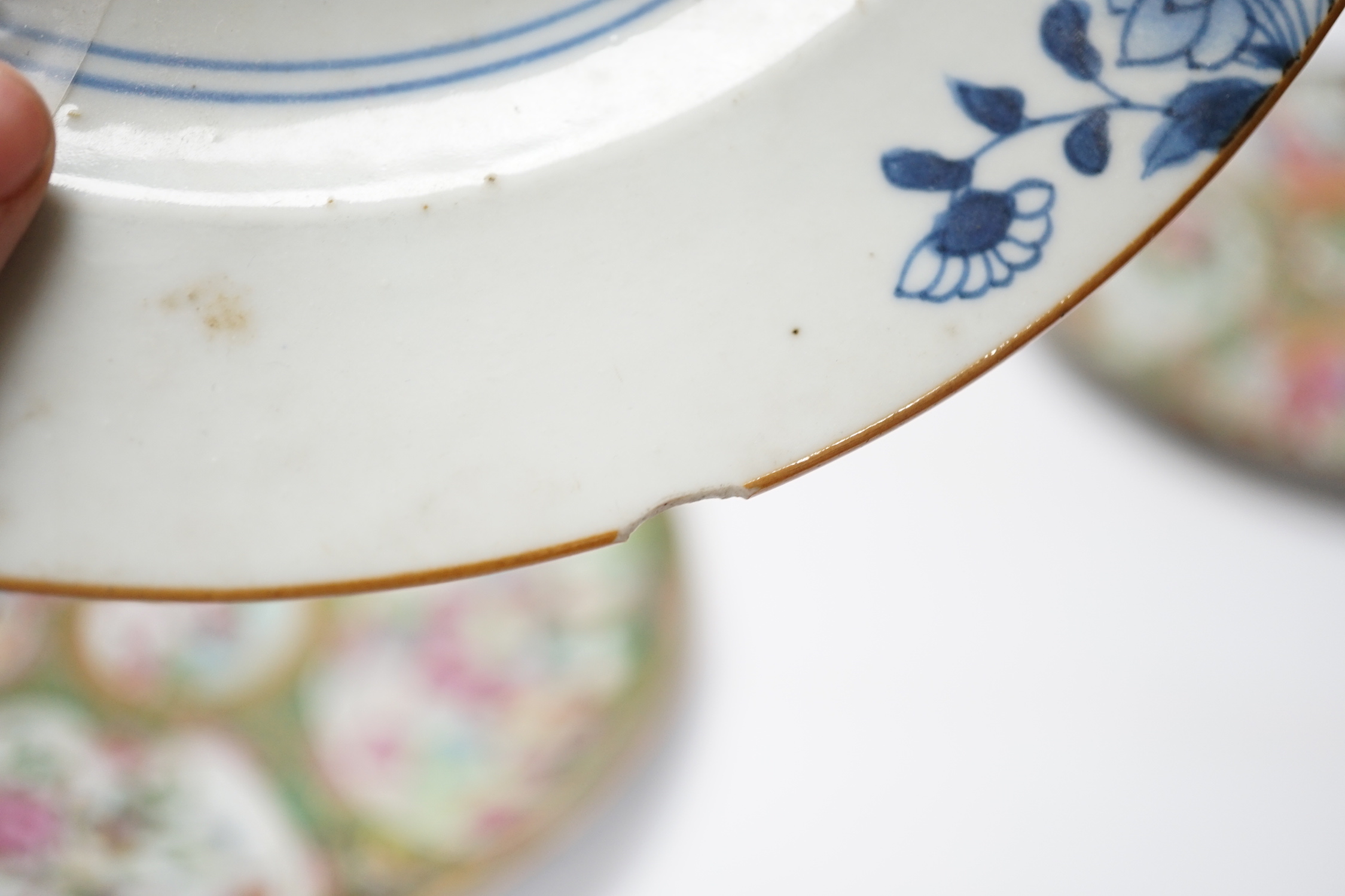 Two 19th century Chinese famille rose plates and an 18th century blue and white plate, 24cm in diameter